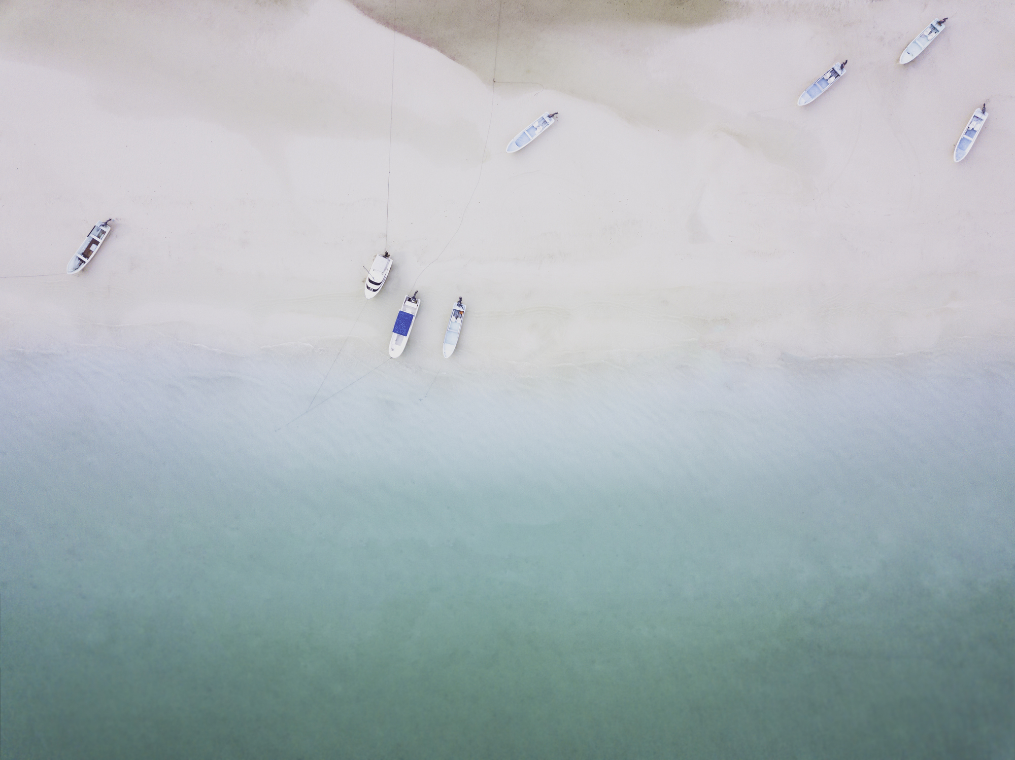 Aerial view of a serene beach with few boats anchored near the shore