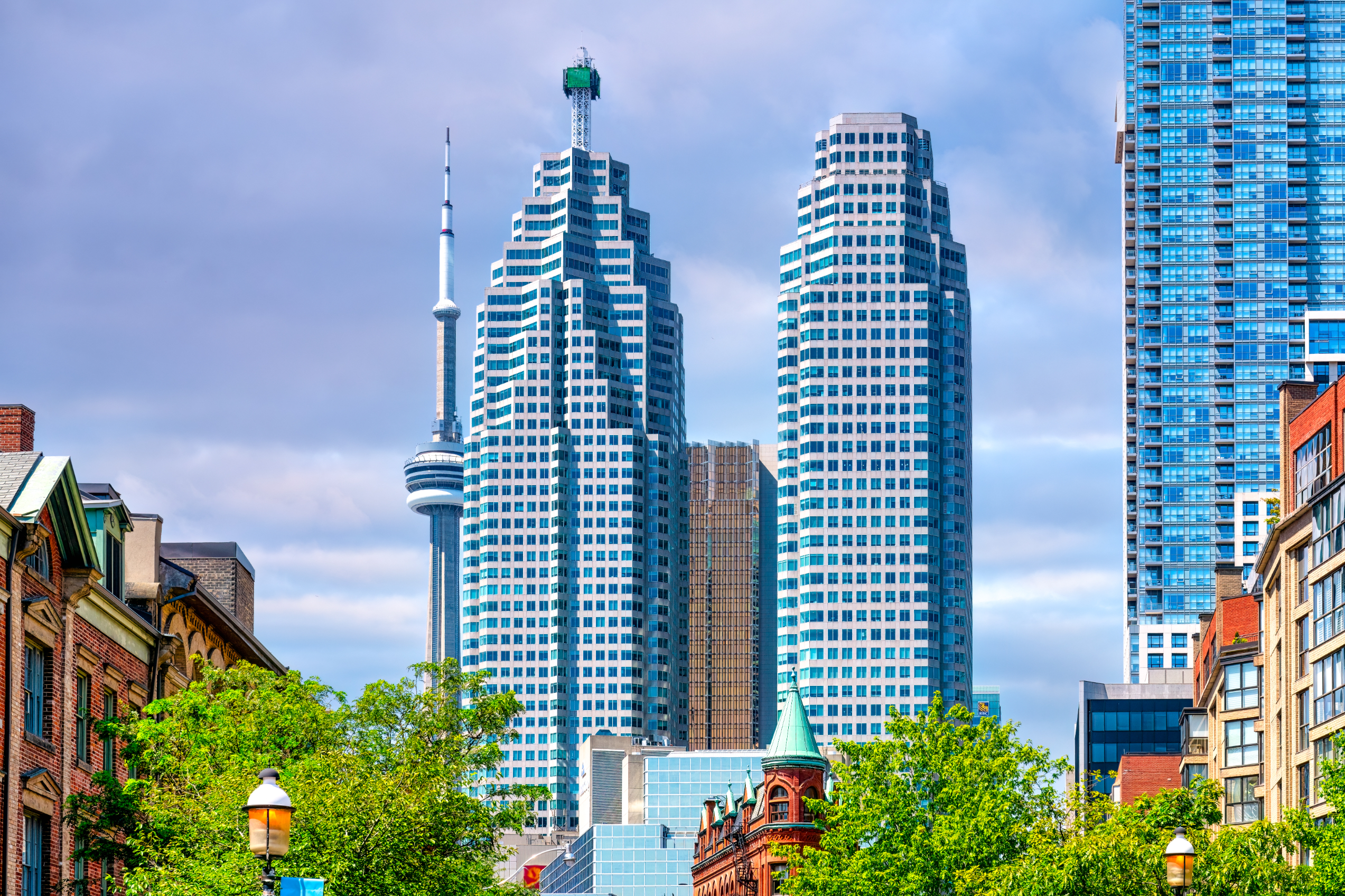 Skyline of downtown Toronto featuring the CN Tower and surrounding high-rise buildings with greenery in the foreground