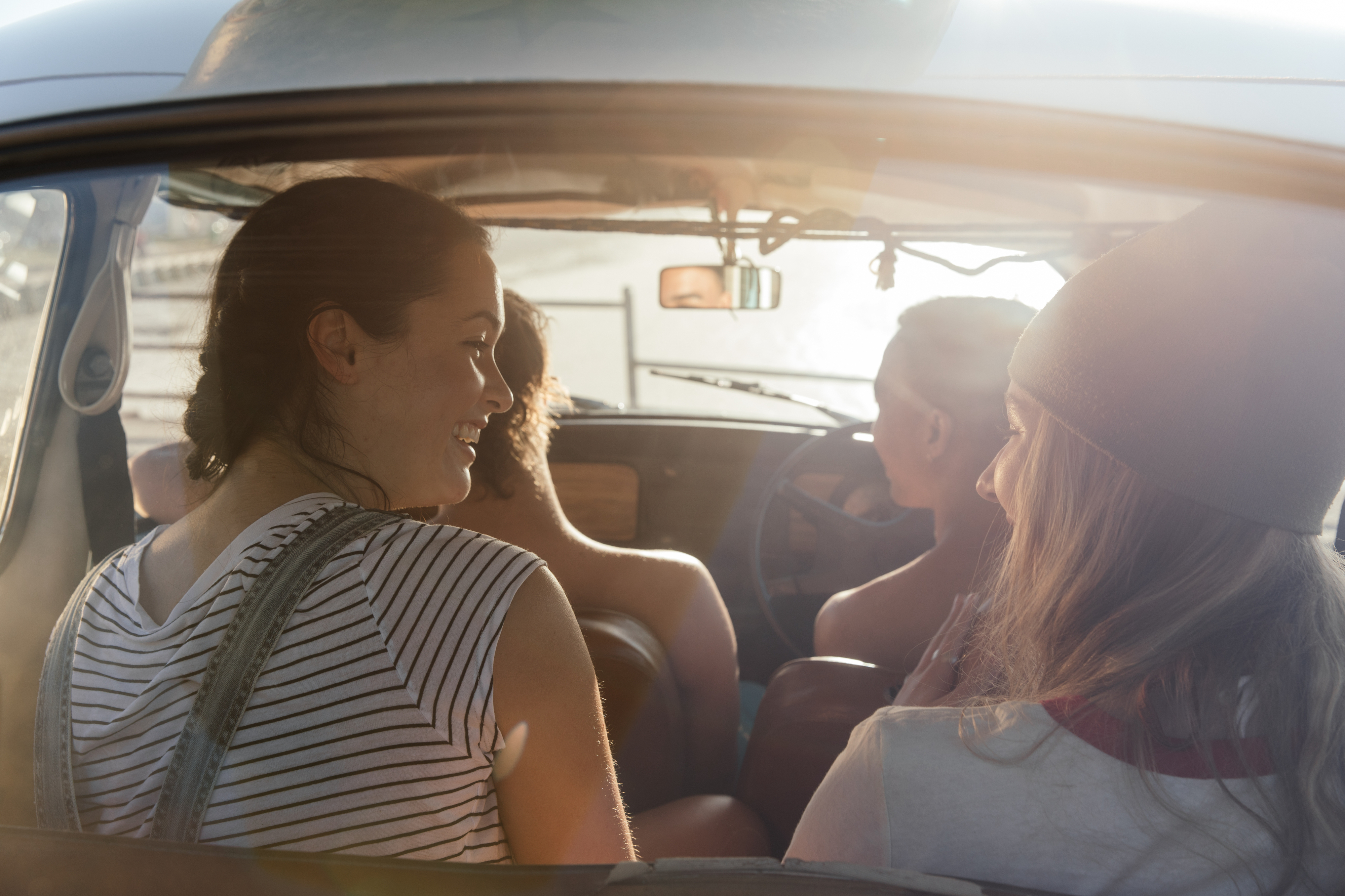 Four people are sitting in a car, with two in the front and two in the back. They appear to be enjoying a conversation. Names not known