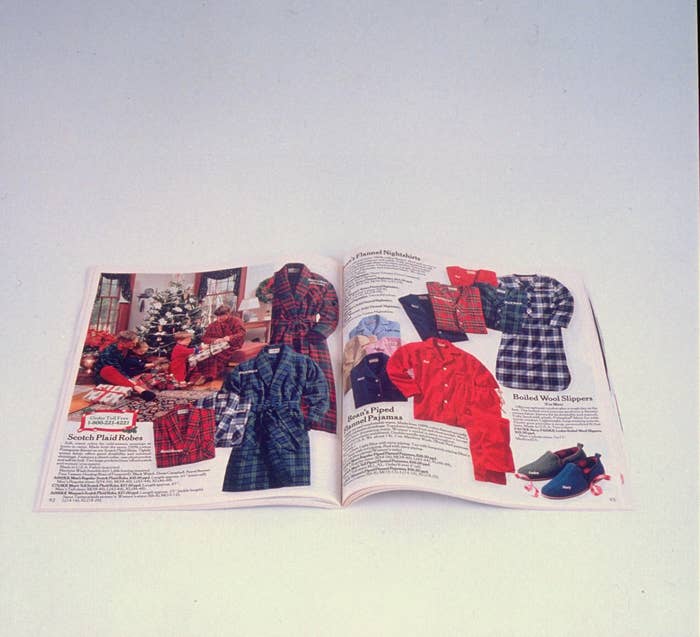 Open catalog showing various plaid robes, wool slippers, pajamas, and a holiday scene. Some descriptions and prices are visible but mostly unreadable due to the image size