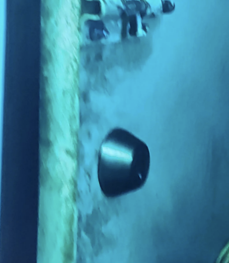 A scene from the movie "Interstellar" shows two astronauts exploring an icy and rugged surface with a large, dark metallic device partially buried in the ground