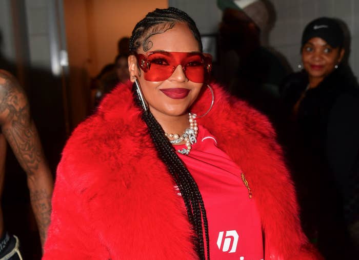 Ashanti wearing glasses and a fur coat over a Balenciaga outfit, smiling and posing for the camera