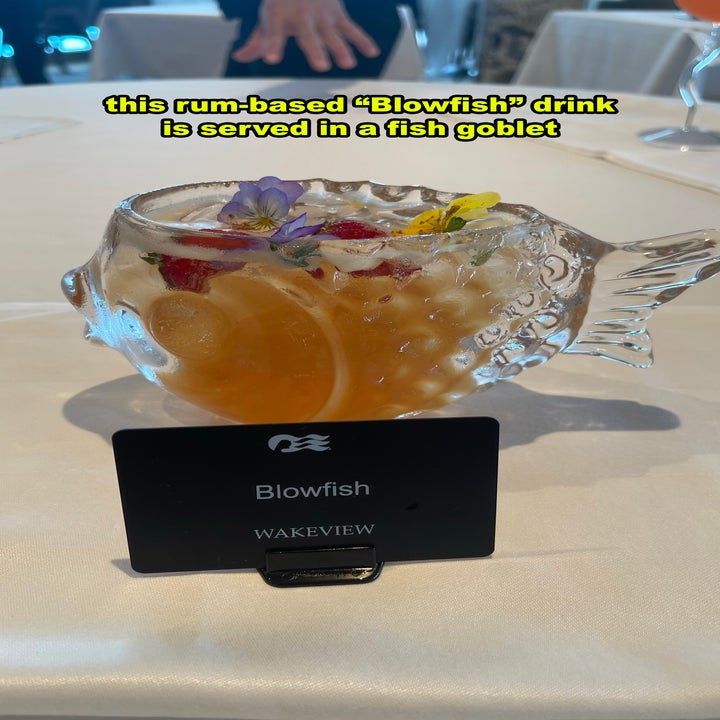 Fish-shaped glass goblet holding a rum-based drink called "Blowfish." Decorated with flowers and fruit. Black label reads "Blowfish" and "WAKEVIEW."