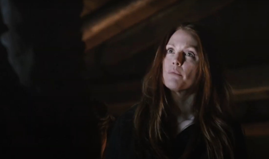 Julianne Moore, wearing a dark outfit, stands indoors looking upwards with a focused expression