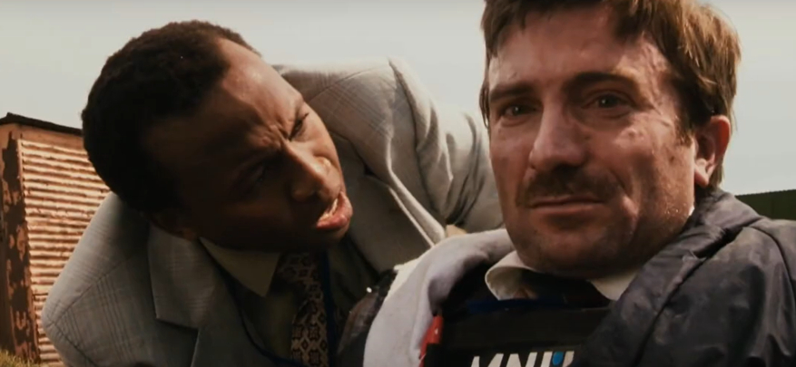 Two men appear in a dramatic scene; one looks concerned, the other apprehensive. The man on the right wears a protective vest labeled "MNU"