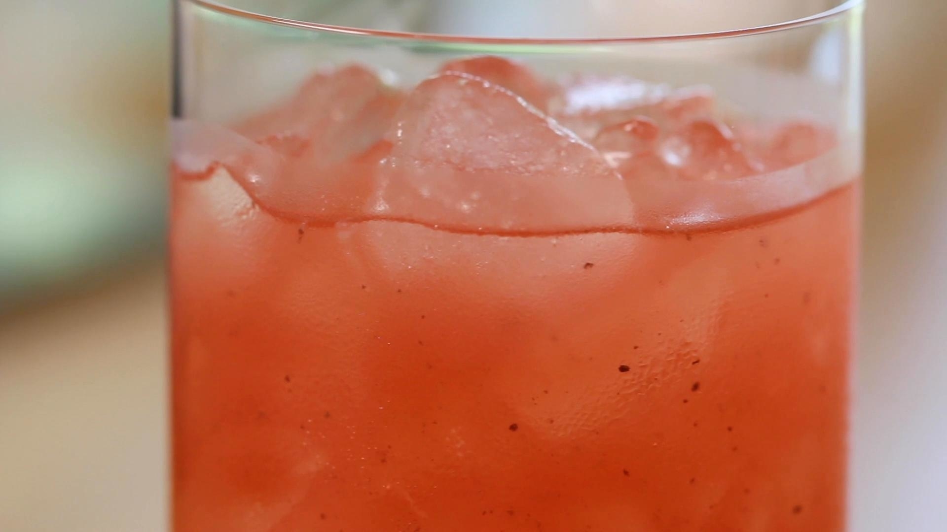 Close-up of a refreshing beverage with ice cubes, likely a fruit punch or cocktail, served in a glass