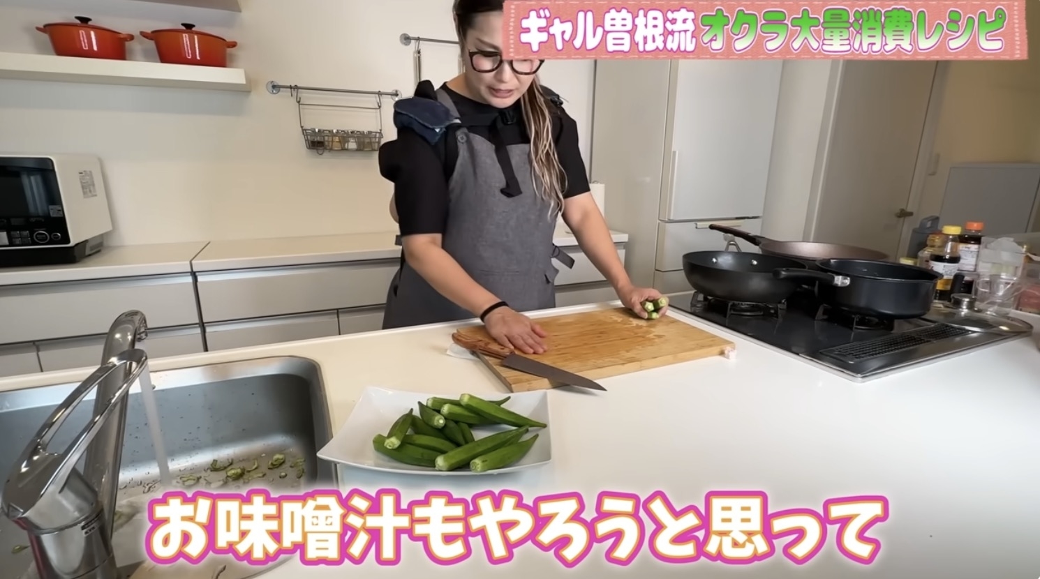 キッチンでエプロンを着た若い女性がオクラを切っている。テキストには「お味噌汁もやろうと思って」と書かれている。