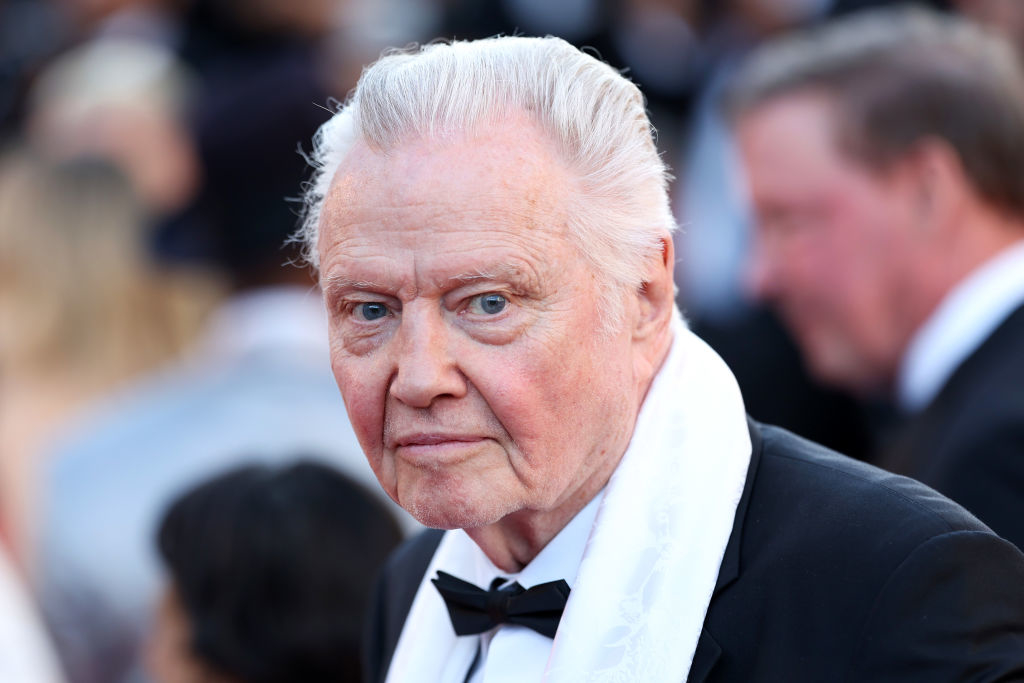 Jon Voight in formal attire with a bow tie and white scarf at a public event. Background shows other people