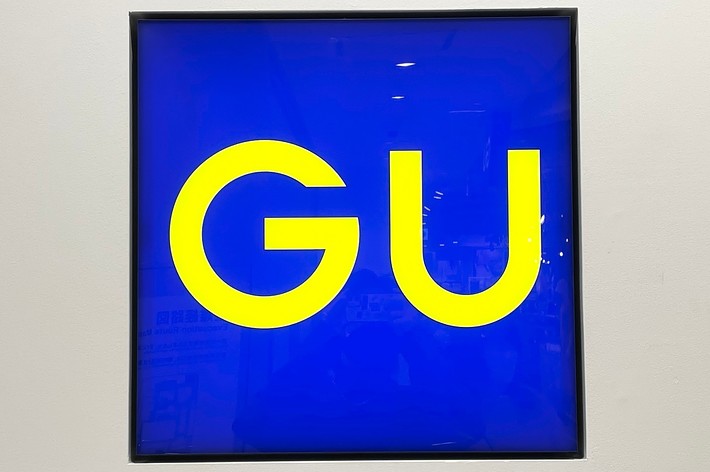 GU sign with yellow letters on a blue background
