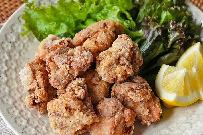 皿に盛られた唐揚げとレモンのスライス、グリーンリーフサラダ。