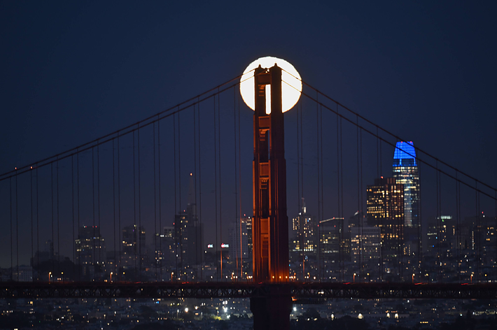 The image shows side-by-side night views: the Statue of Liberty holding up the moon and the moon appearing on top of the Golden Gate Bridge
