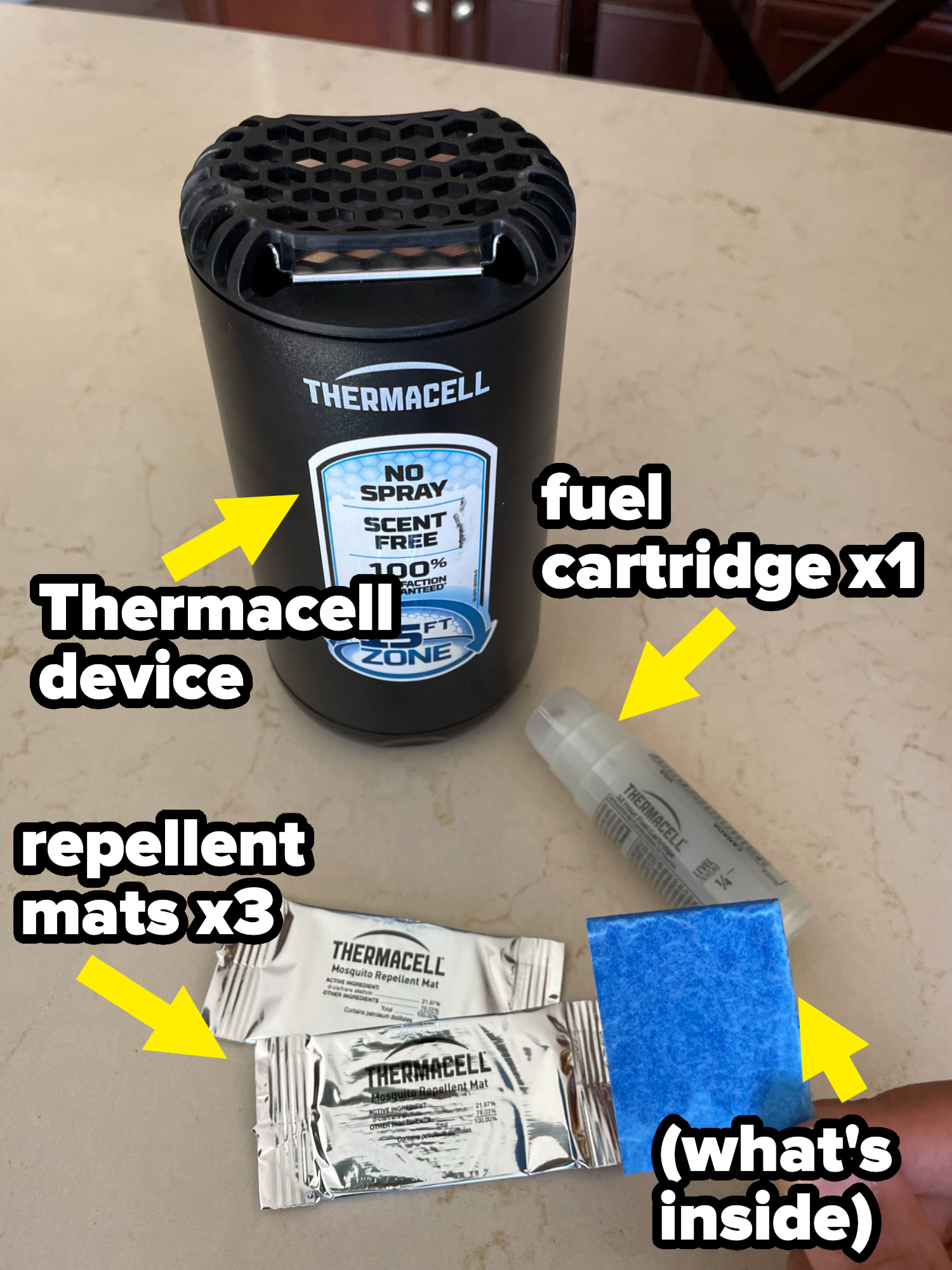 Thermacell mosquito repellent device with two foil-wrapped repellent mats, a blue mat, and a small fuel cartridge laid out on a countertop