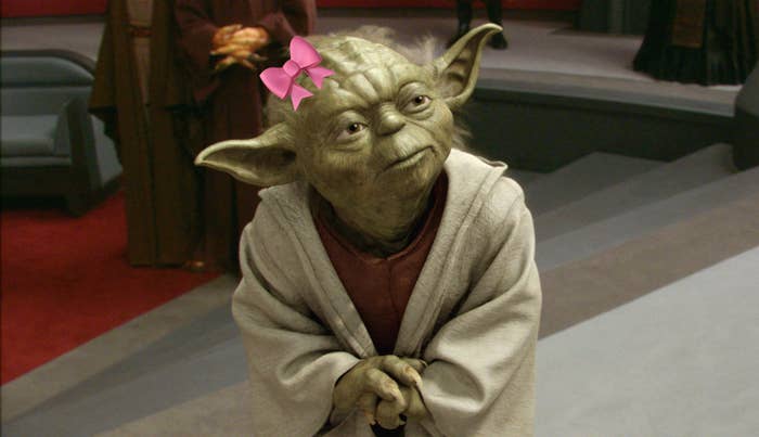Yoda, a character from Star Wars, stands thoughtfully in a room with other individuals in the background