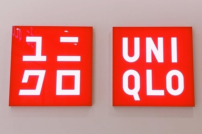 Two red signs with white text: one sign has Japanese characters, the other says &ldquo;UNIQLO.&quot;