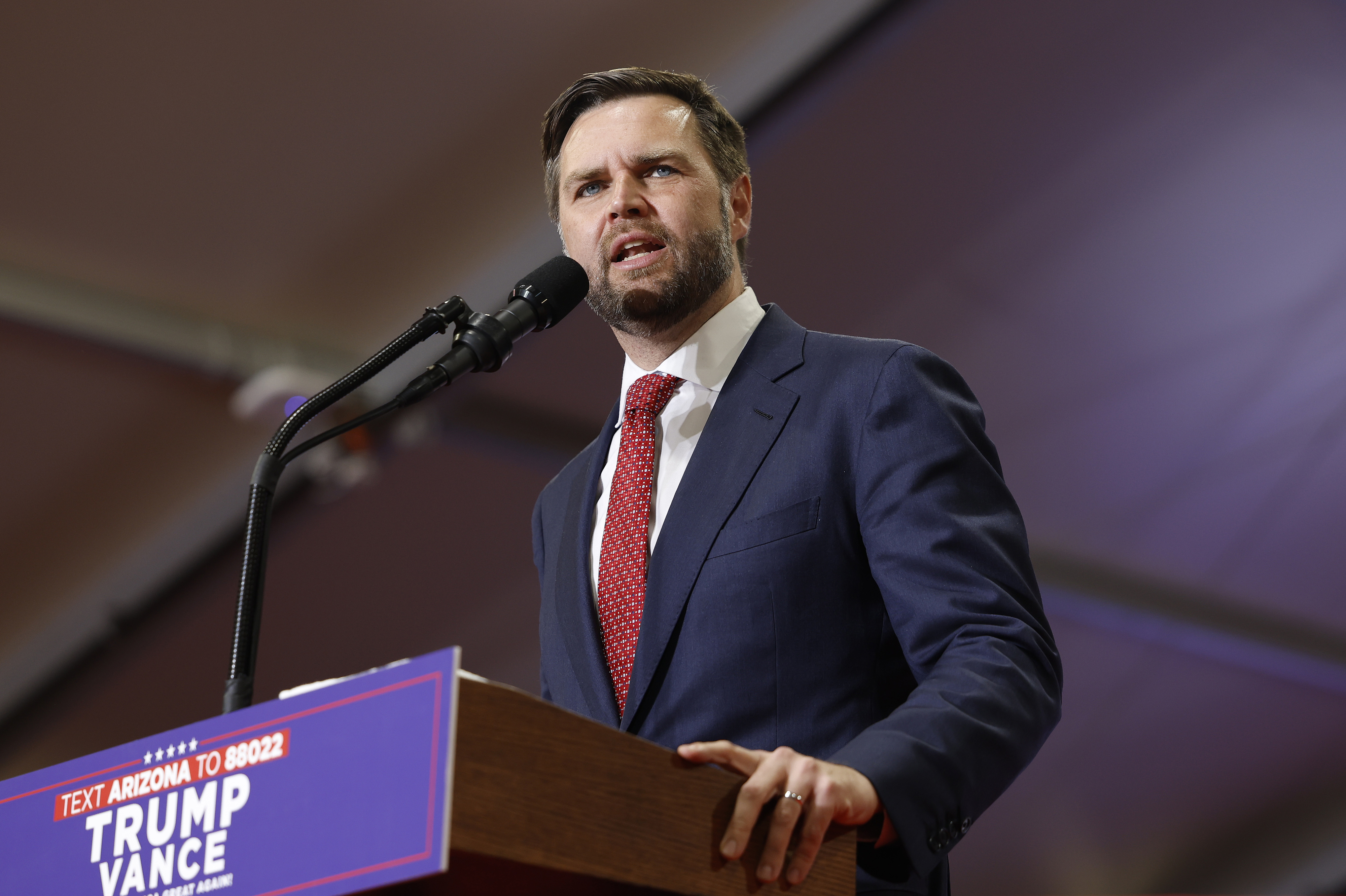 J.D. Vance speaks at an event, wearing a suit and tie