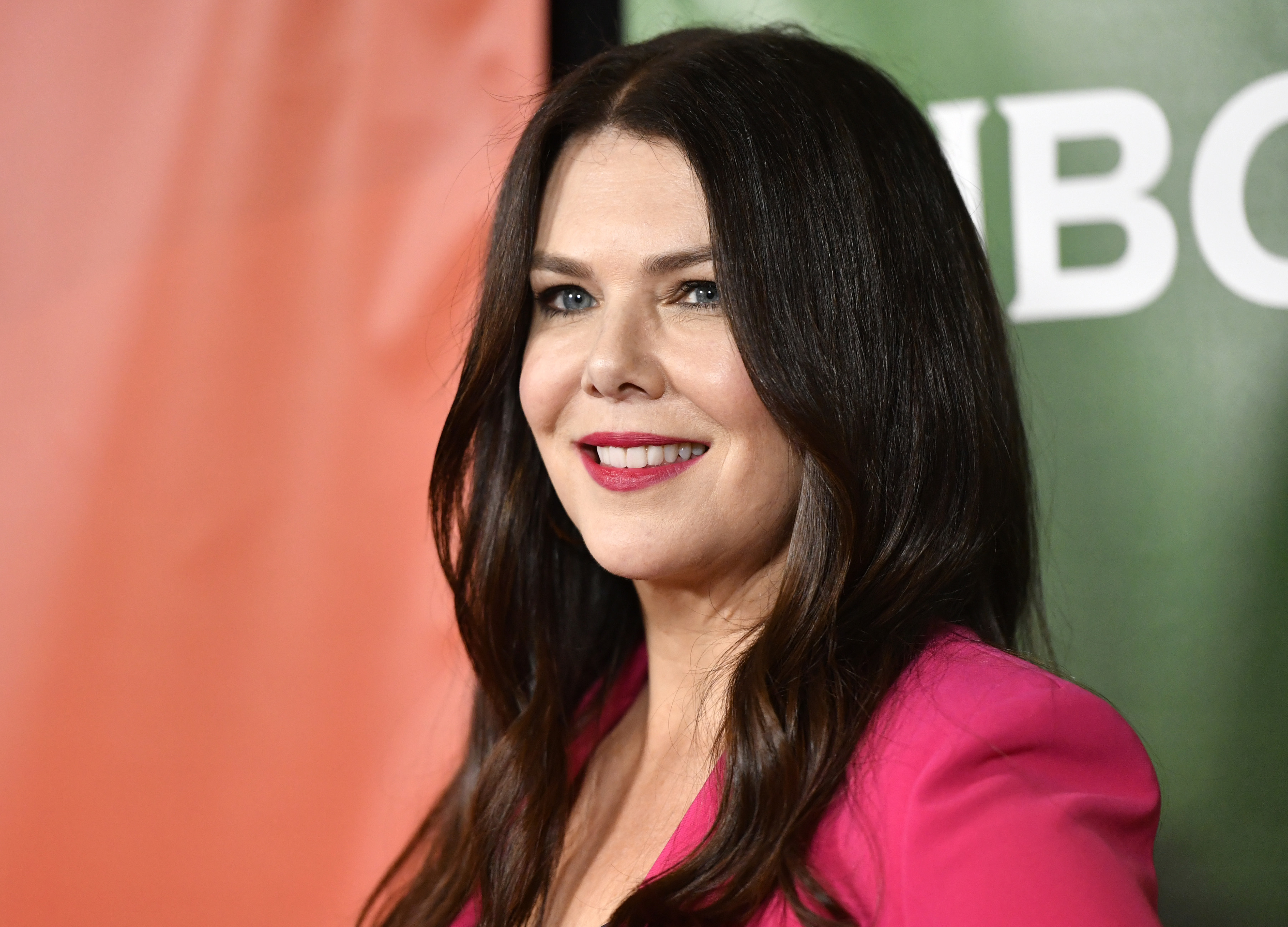 Lauren Graham smiles while posing on the red carpet in a chic, tailored outfit with a blazer