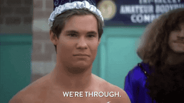 Adam DeVine, shirtless and wearing a cap, says "We're through" in a scene from a show. A person in the background wears a purple outfit
