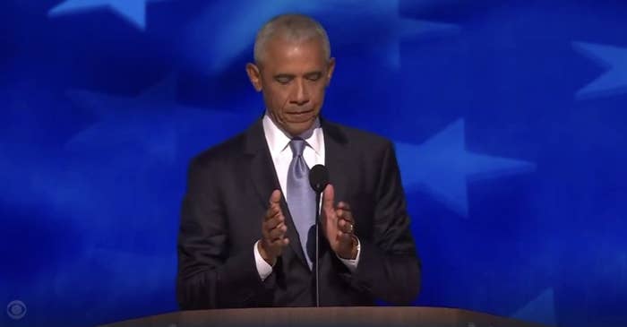 Barack Obama stands on stage, hands apart, addressing the DNC