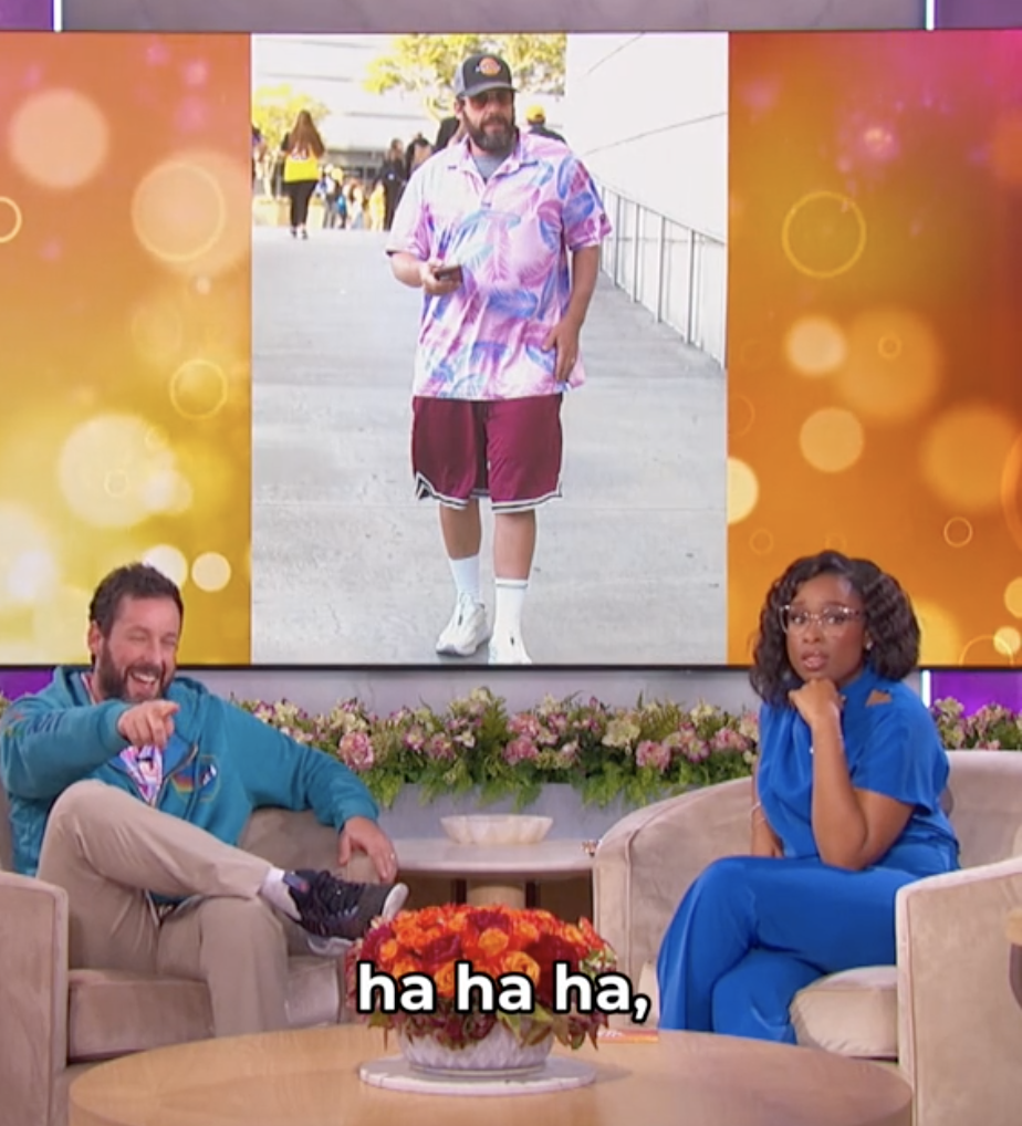 Adam Sandler and Jennifer Hudson share a laugh on a talk show set. A large photo of Sandler in casual clothing is displayed behind them. Subtitles read "ha ha ha"