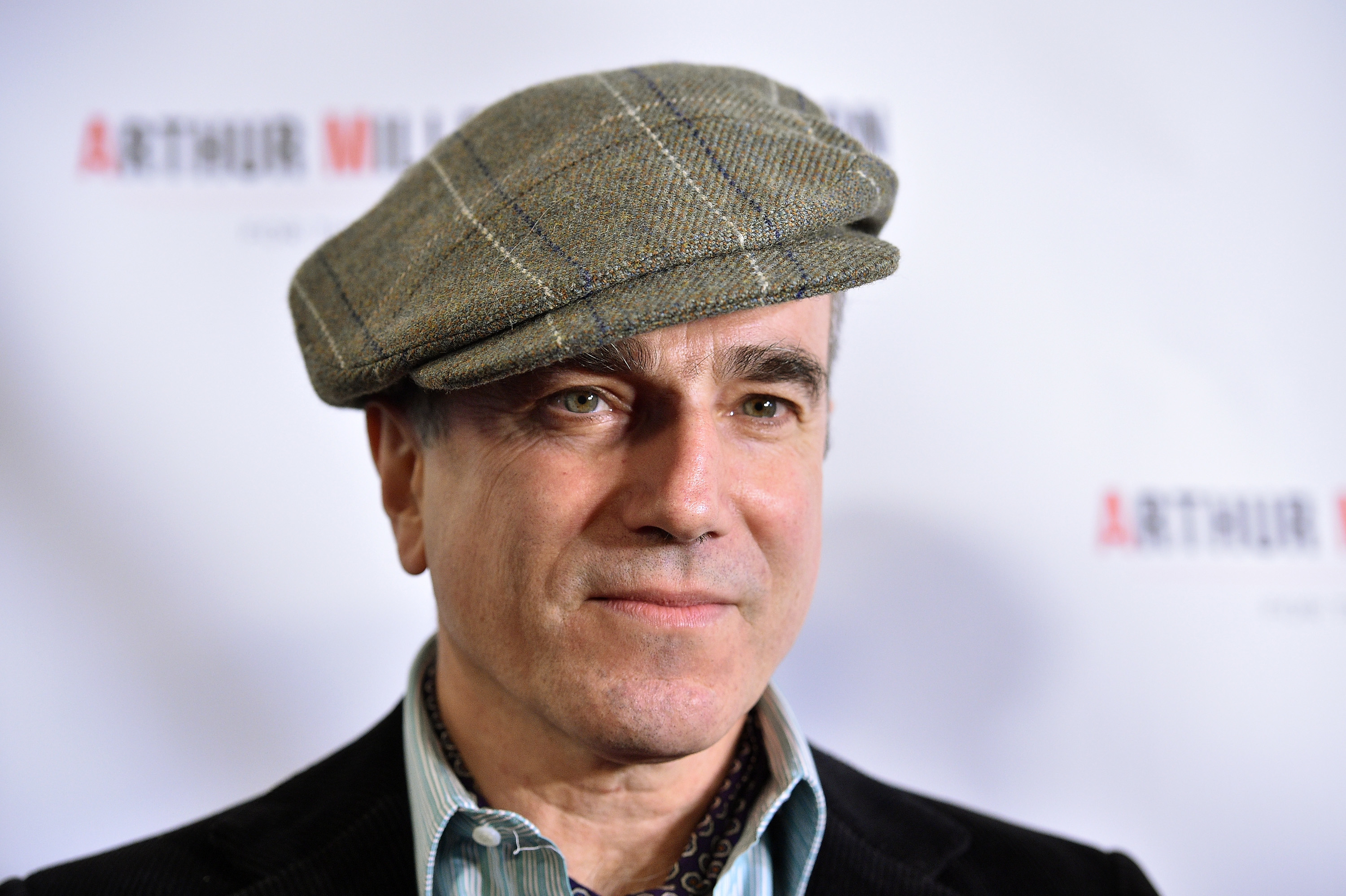 Daniel Day-Lewis wears a flat cap and a striped shirt with a dark blazer at an Arthur Miller event