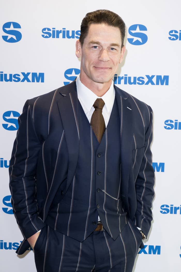 John Cena at a SiriusXM event, wearing a pinstriped three-piece suit with a shirt and tie