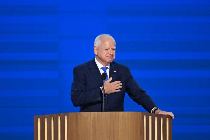 Tim Walz standing at a podium with one hand on his chest delivering his speech