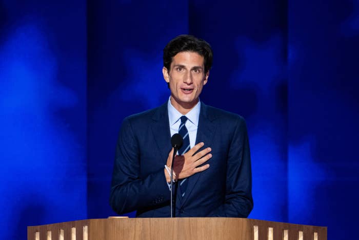 Jack stands behind podium, hand on chest, speaking into microphone against a starry background