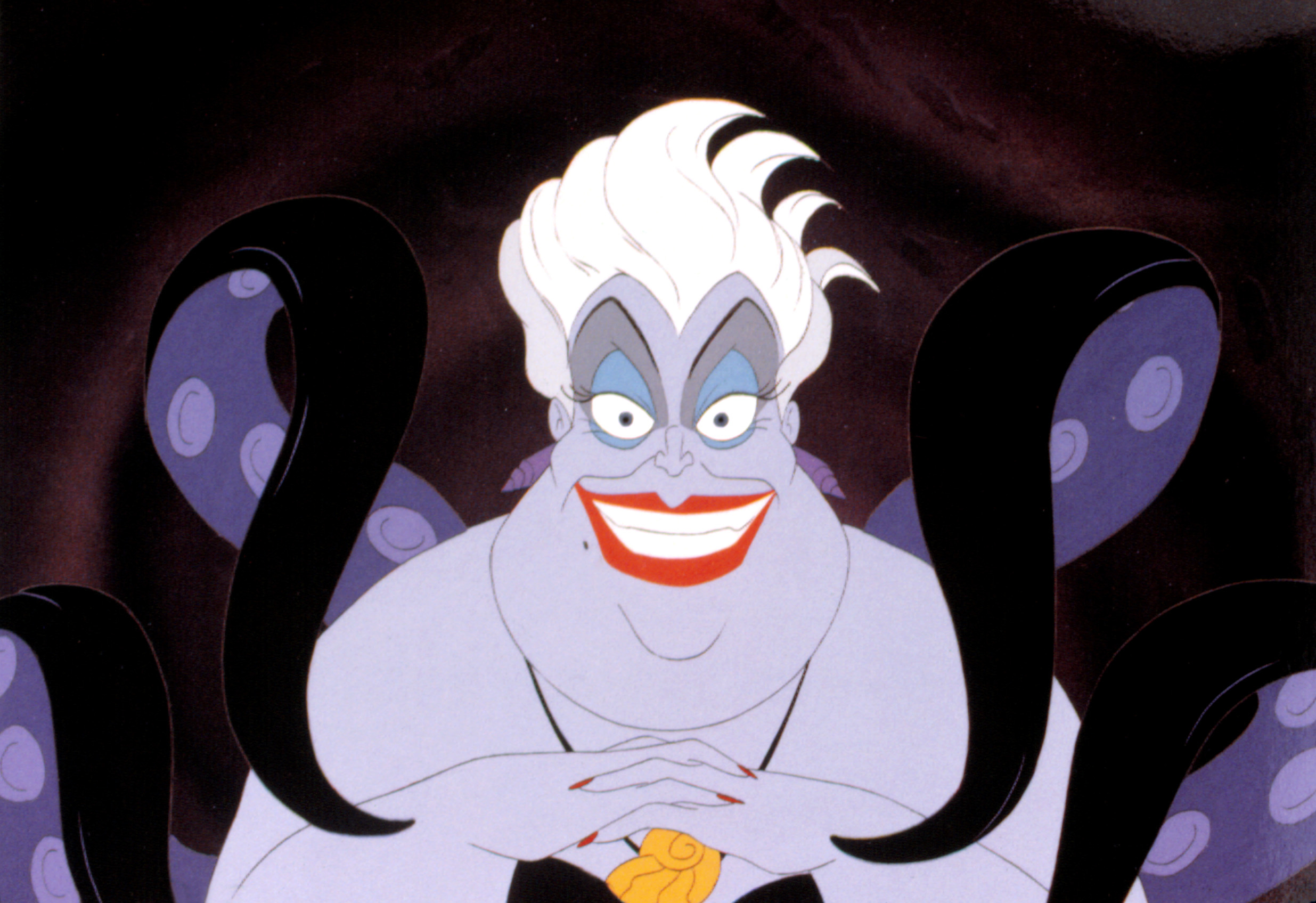 Ursula from "The Little Mermaid" with a sly smile, white hair, blue eyeshadow, and black tentacles, clasping her hands together