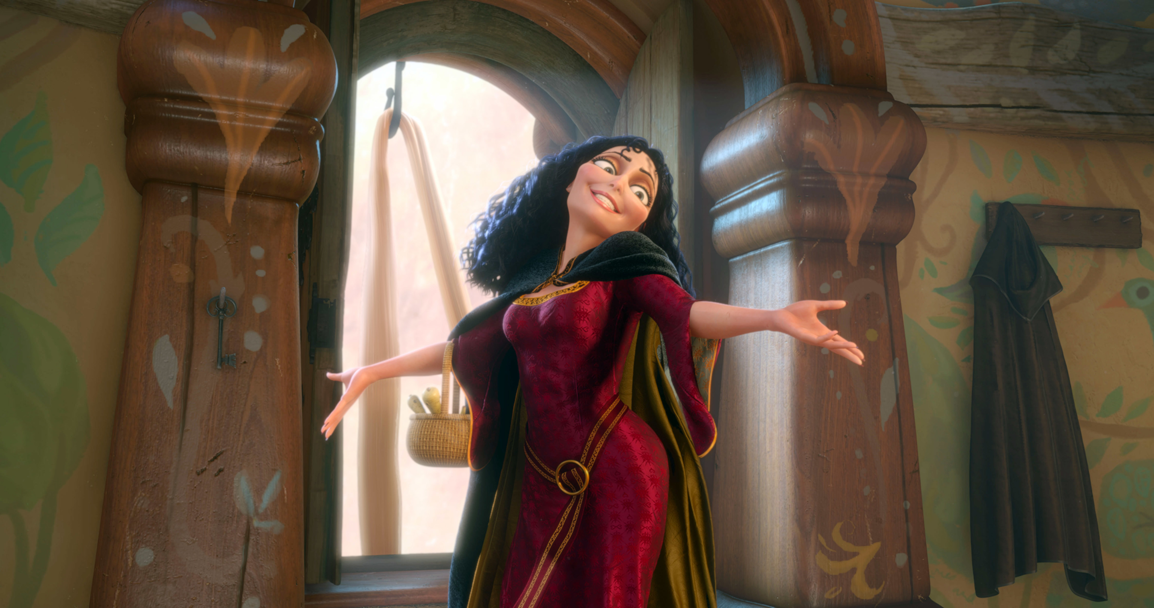 Mother Gothel from Disney's "Tangled" stands happily by an open window with her arms outstretched, wearing a medieval-style gown