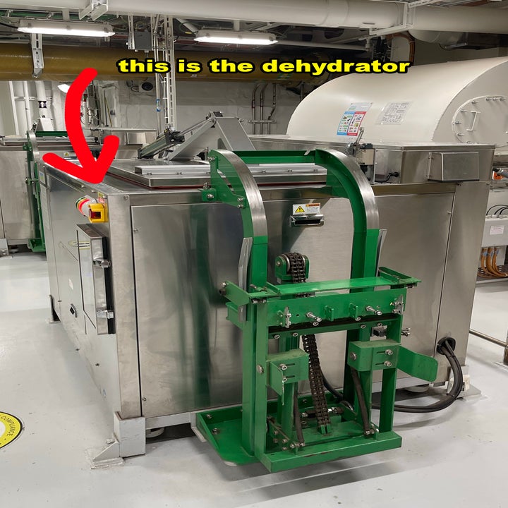 Metallic industrial dehydrator machine with green components. Red arrow pointing to a button with text "this is the dehydrator."