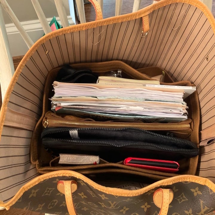 A Louis Vuitton bag containing files, documents, a zipper pouch, and notebooks