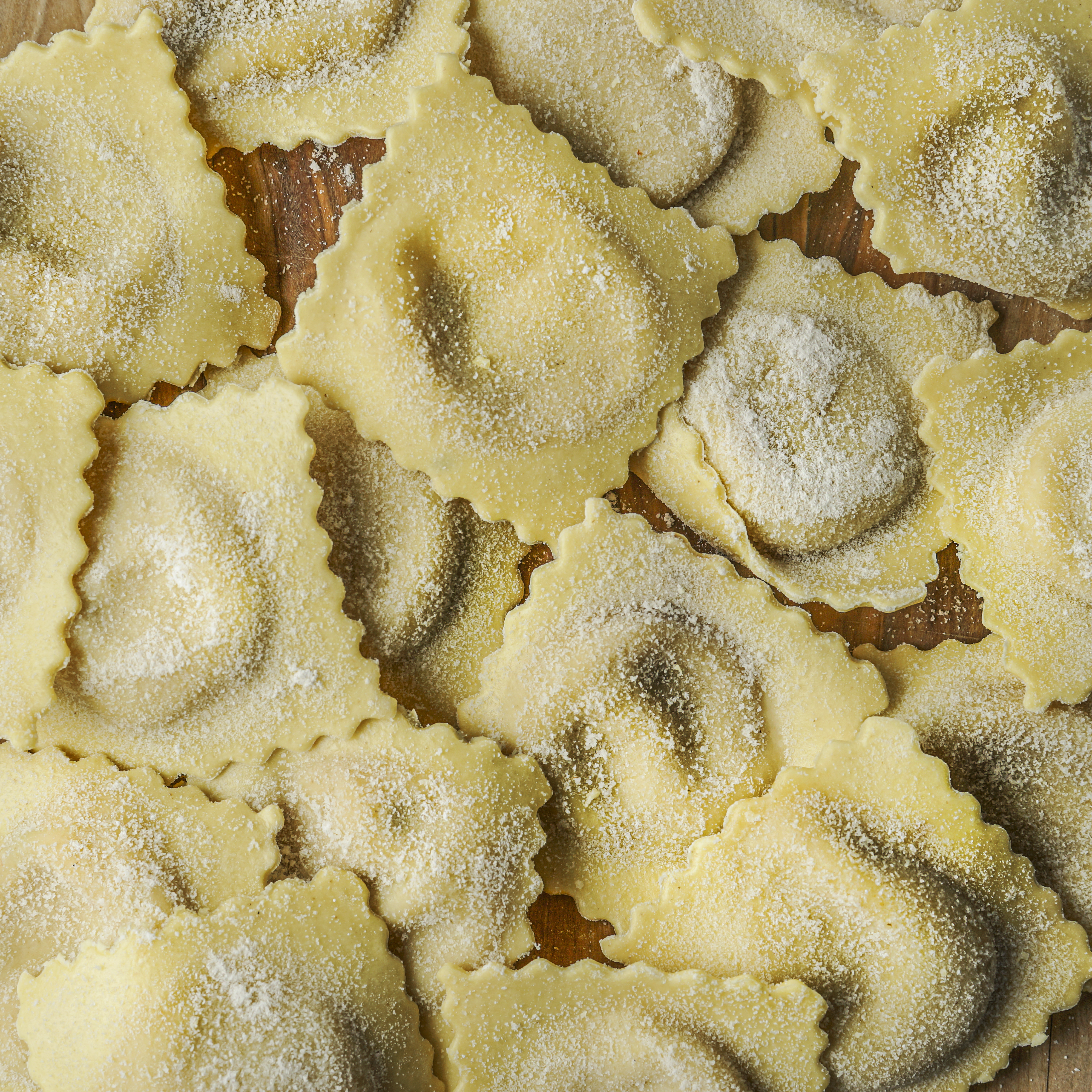 Close-up shot of uncooked ravioli scattered on a flat surface, covered in flour