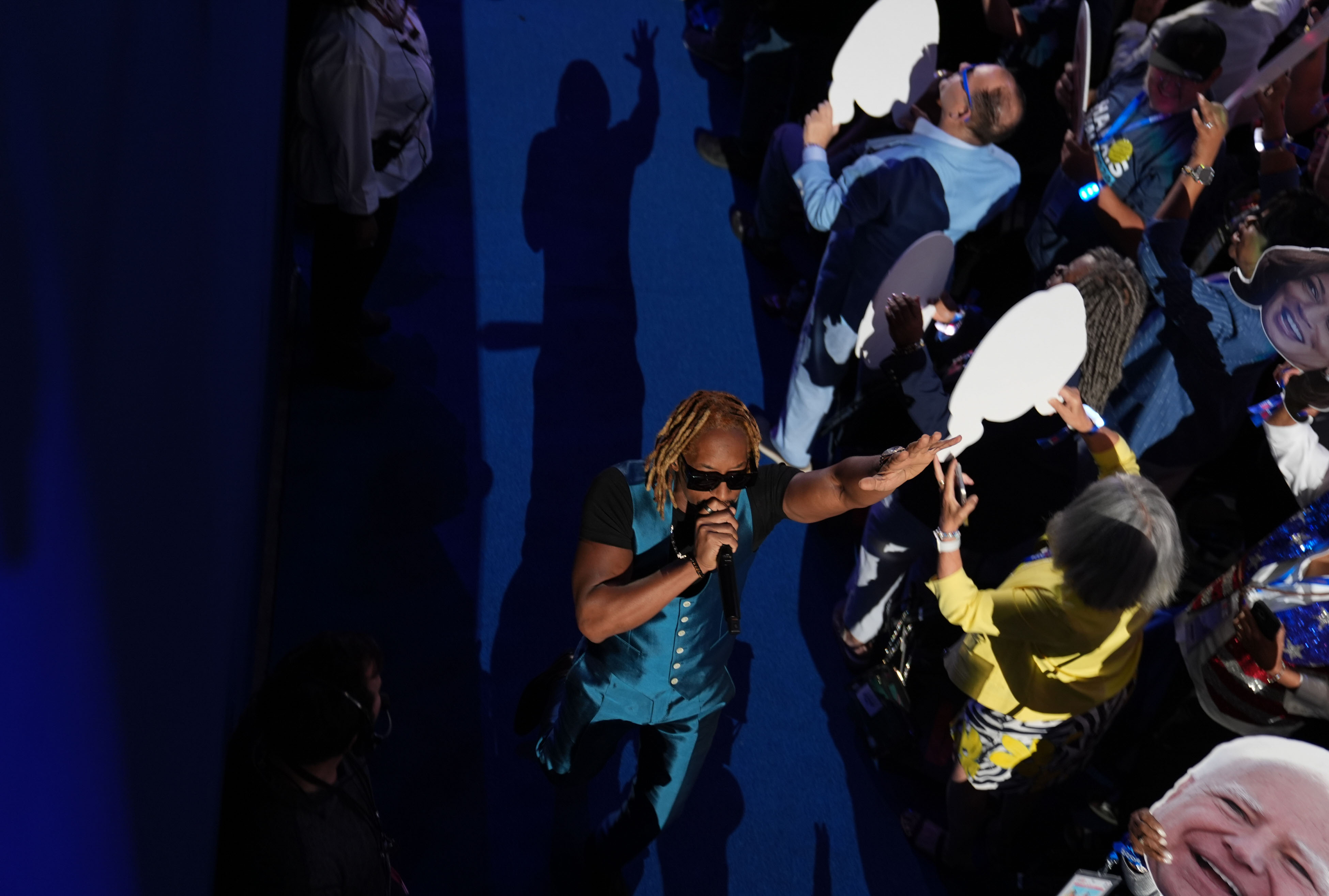 Steve Wonder performs on stage, surrounded by an audience holding fans with his face on them
