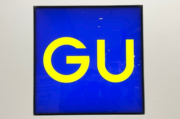 GU store sign with yellow text on a blue background