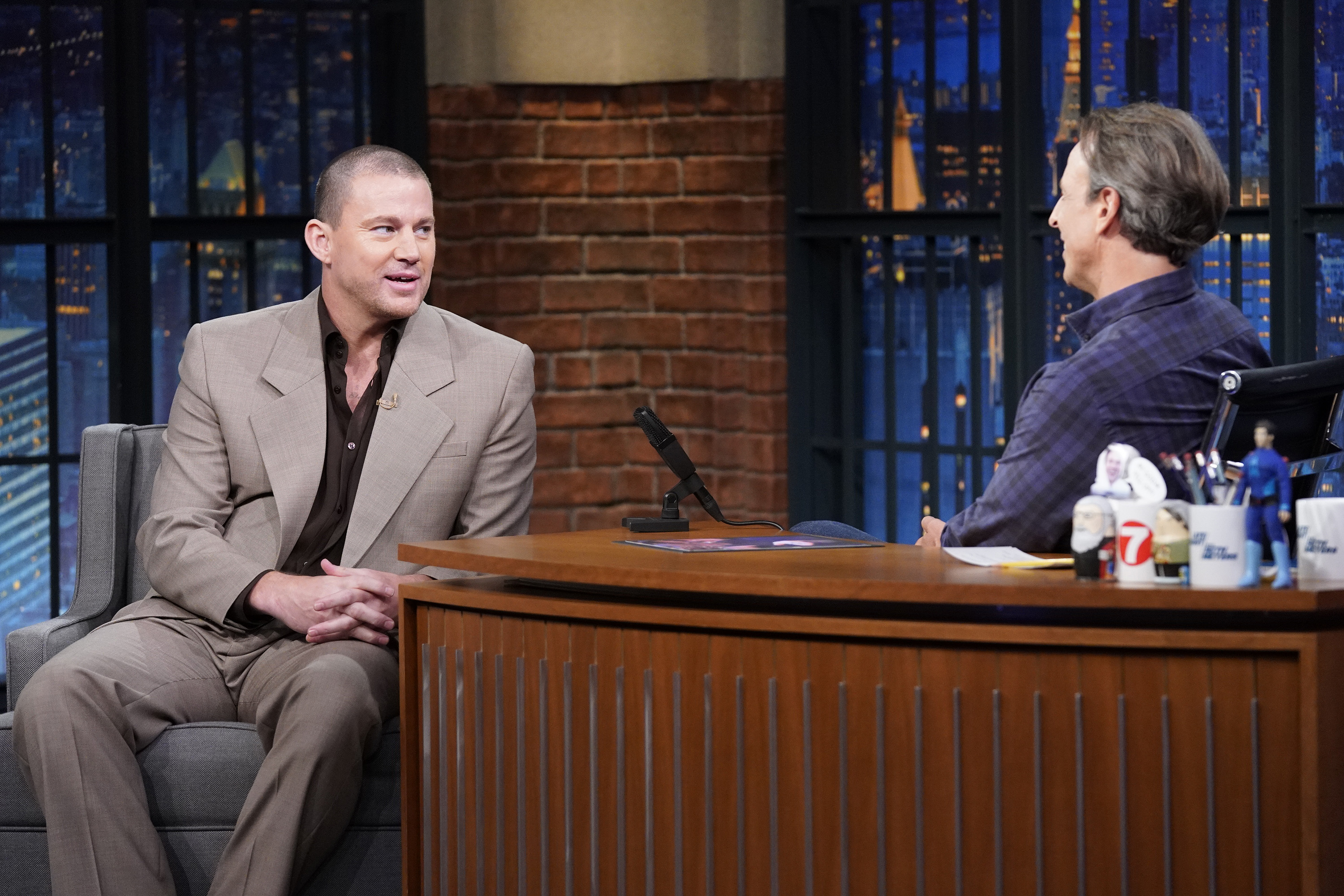 Channing Tatum in a suit talks to host Seth Meyers on the set of "Late Night with Seth Meyers"