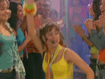 Mujer bailando en una fiesta rodeada de personas aplaudiendo y disfrutando