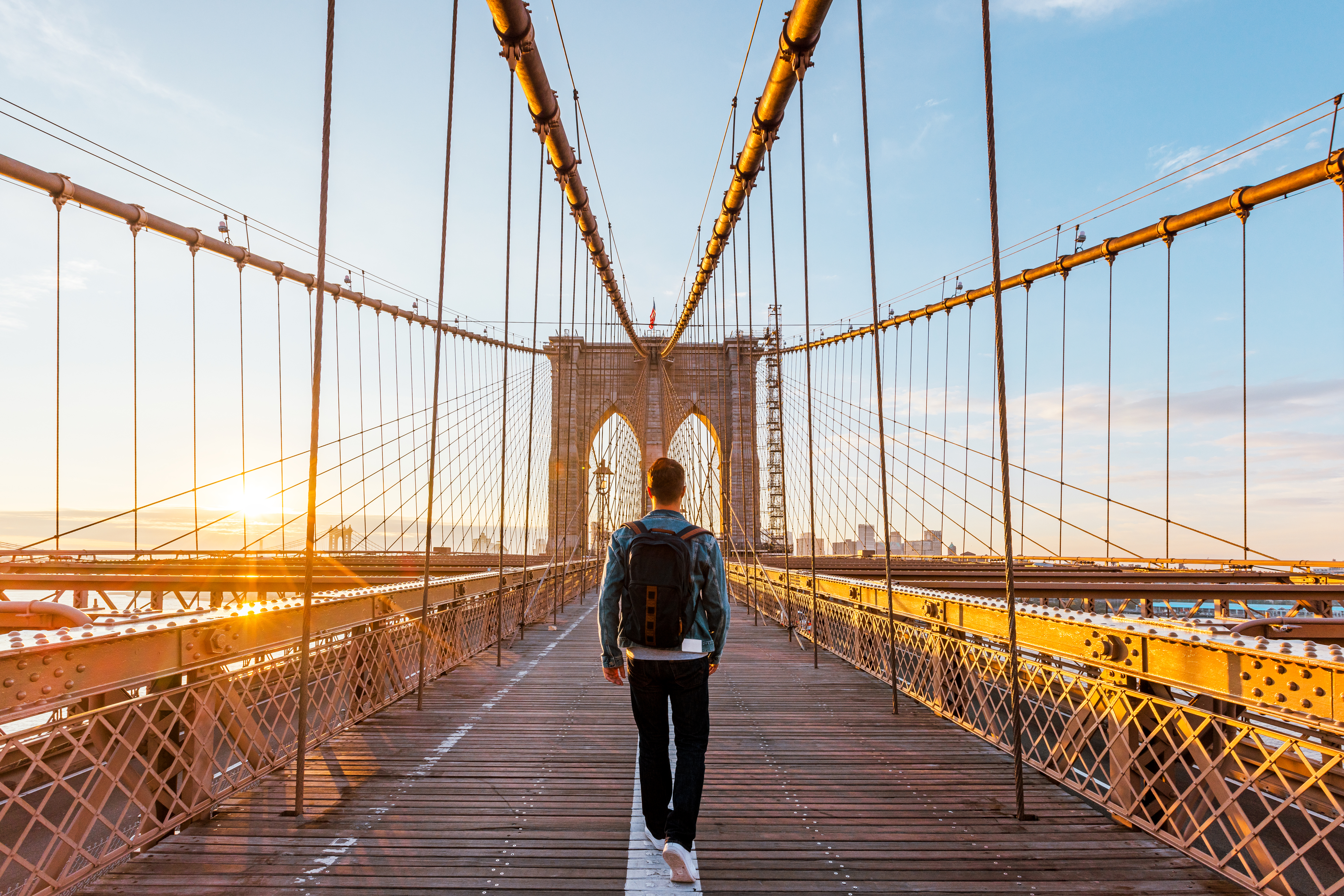 A person walking over the Brooklyn Bridge at sunset while it&#x27;s empty