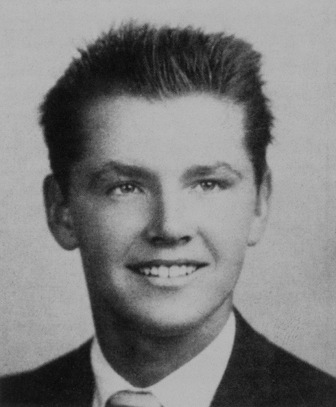 Black and white high school yearbook photo of a smiling young man with short, combed hair, wearing a suit and tie