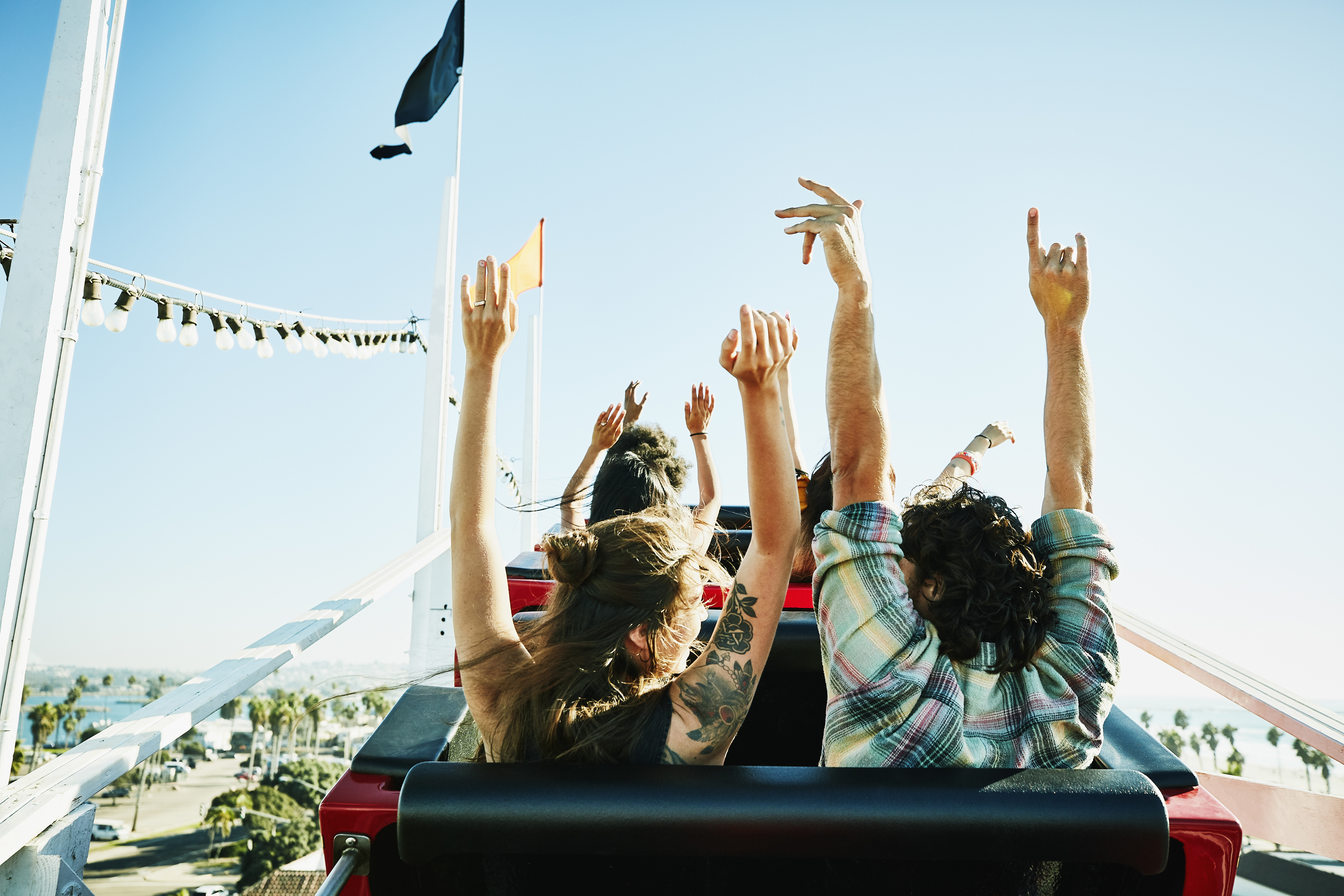 People on a roller coaster with their hands in the air, enjoying the ride