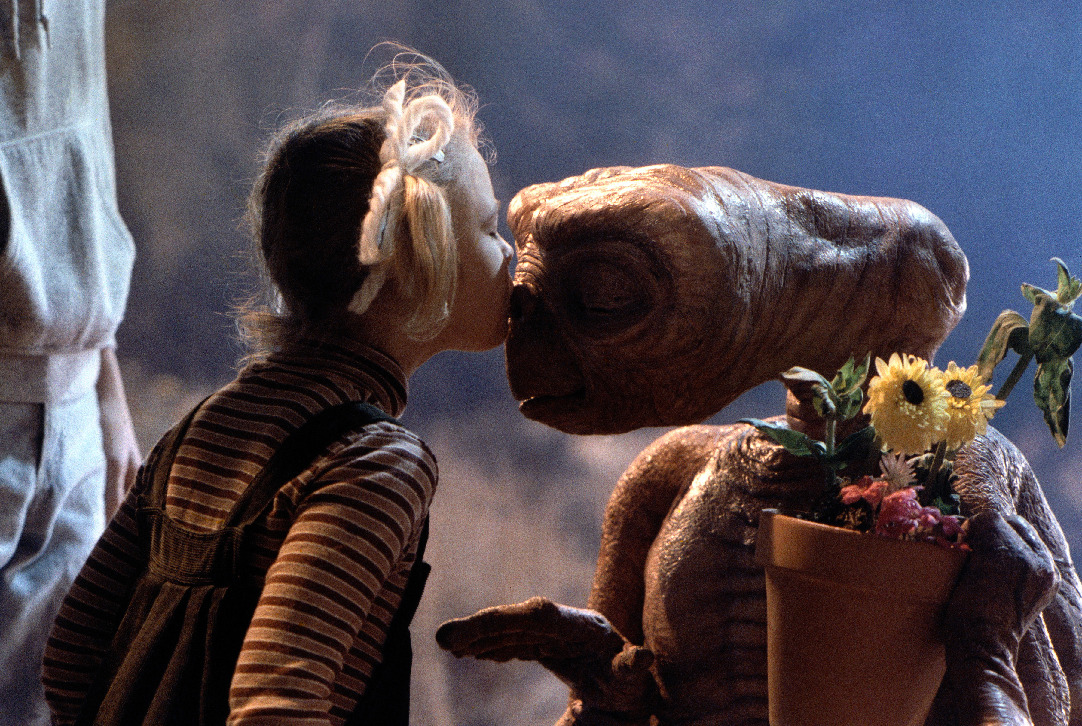 Drew Barrymore kisses E.T., the extraterrestrial, who is holding a pot of flowers in a scene from the movie "E.T. the Extra-Terrestrial"
