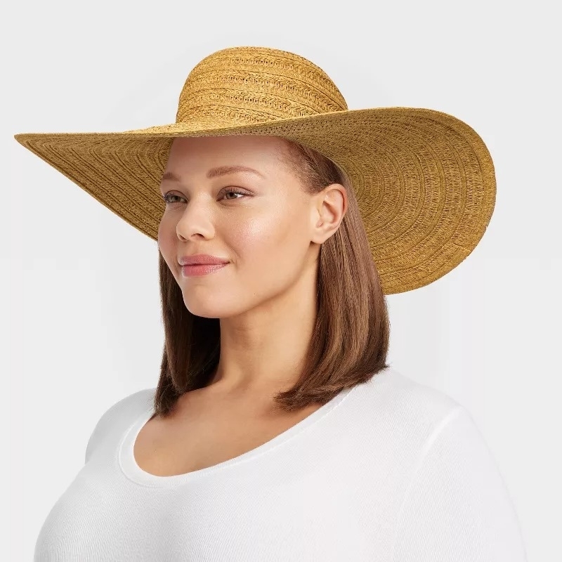 A model wearing a wide-brimmed straw sunhat and a white top