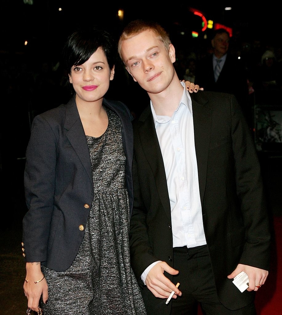 Lily Allen in a blazer over a sparkly dress, and Alfie Allen in a suit with an unbuttoned shirt, posing together on a red carpet