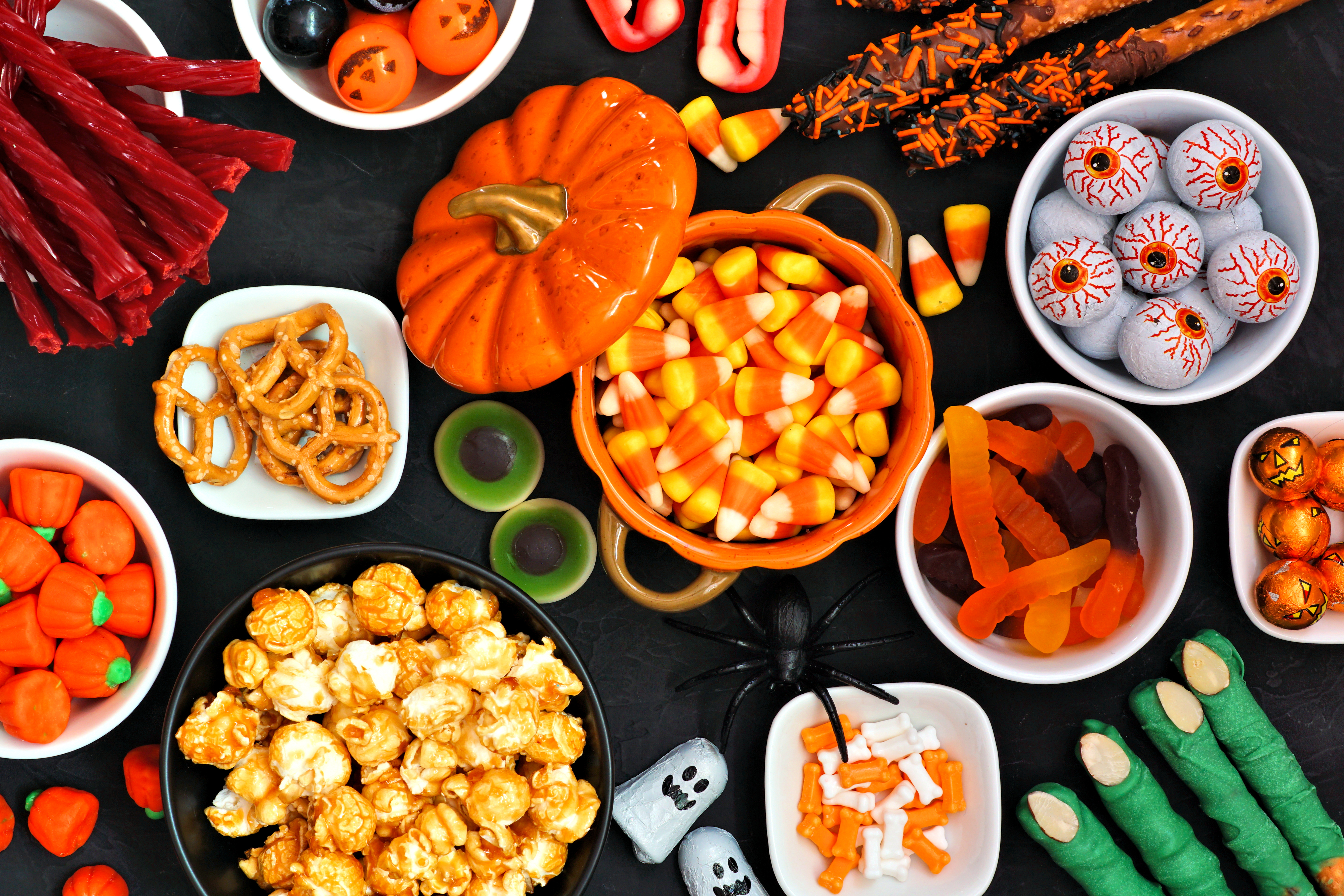 An array of Halloween-themed treats, including candy corn, popcorn, pretzels, gummies, licorice, and festive decorations