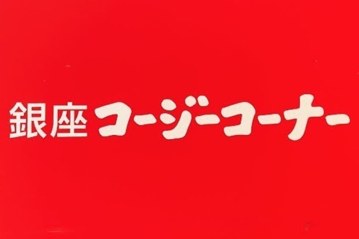 Signage for Ginza Cozy Corner, featuring the name in Japanese characters on a red background with a sleek, metallic frame, mounted on a brick wall