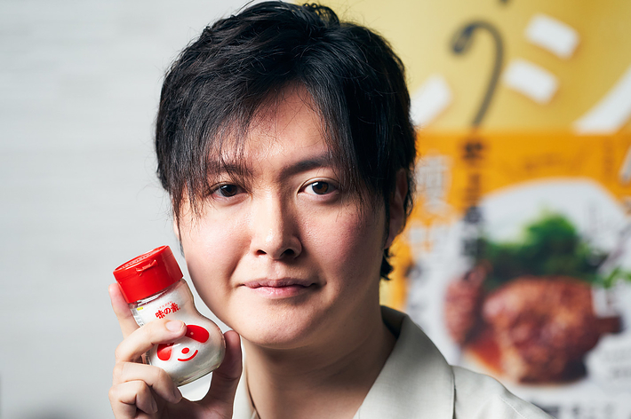男性が調味料のボトルを手に持っている。背景に食品パッケージ。
