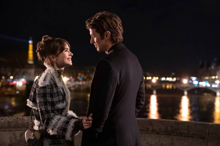 Lily Collins and Lucas Bravo standing by the water with a view of Paris in &quot;Emily in Paris&quot; Season 4