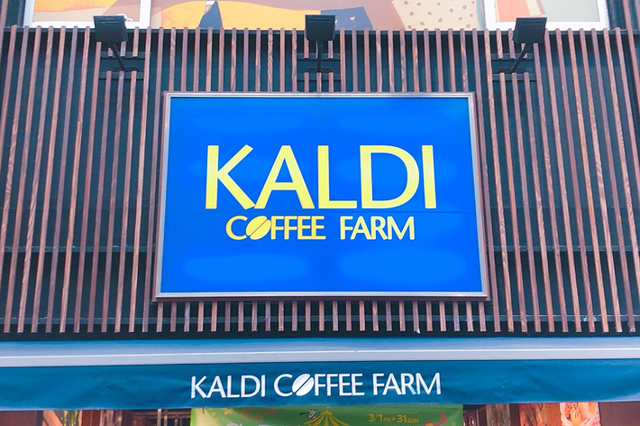 カルディコーヒーファームの店内展示。ワイン、ナッツ、お菓子などが並ぶ棚。背景に広告と季節の装飾が見える。