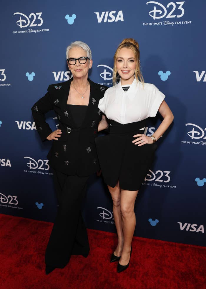Jamie Lee Curtis in a pantsuit and Lindsay Lohan in a shirt and short skirt on the red carpet at the D23 event