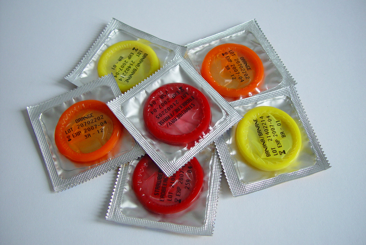 Condoms in various colored packages are arranged in a circular pattern
