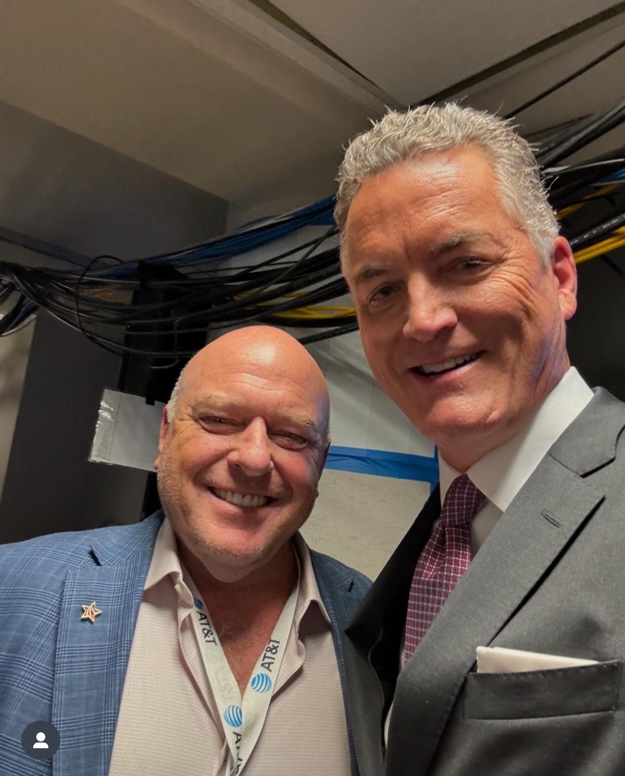 Dean Norris and Jay Glazer smile for a photo, with Dean wearing a blue plaid jacket and Jay in a suit and tie